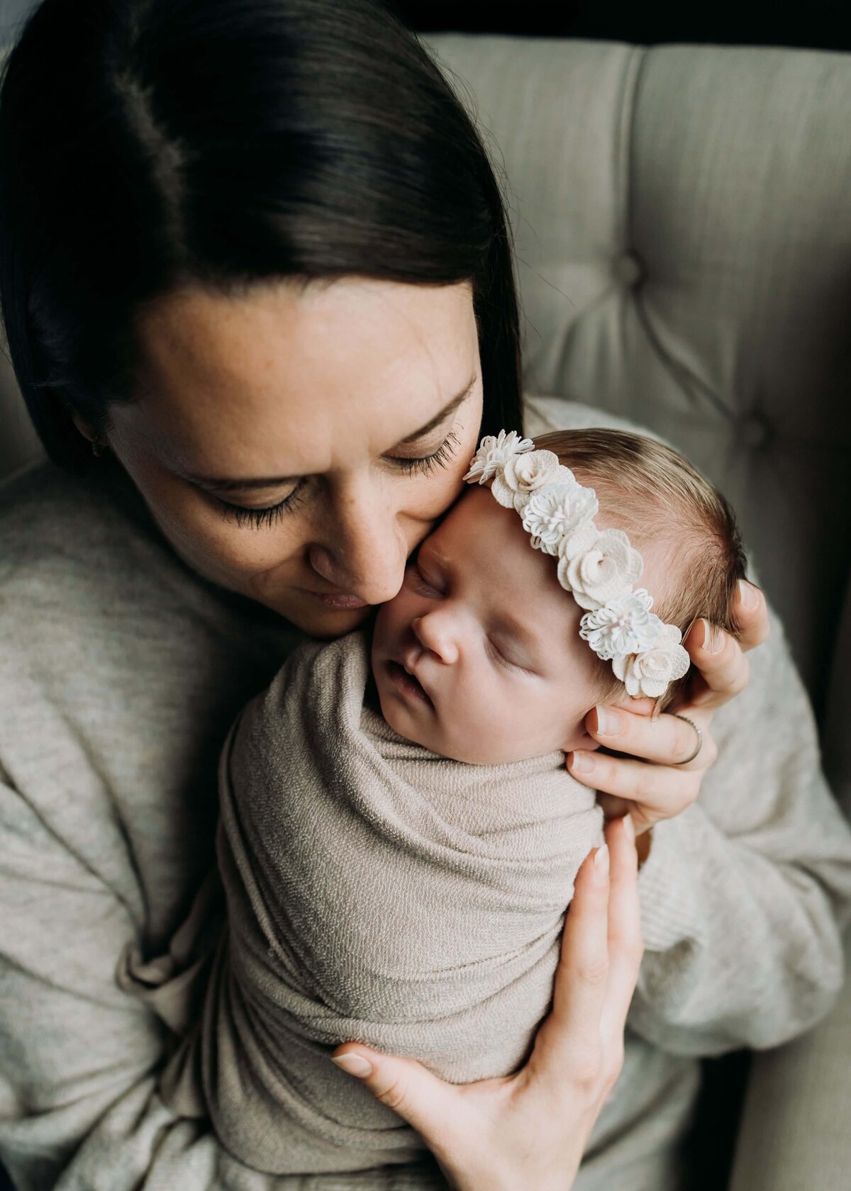 A woman, Pittsburgh newborn photographer, is holding a baby girl wrapped in a blanket.