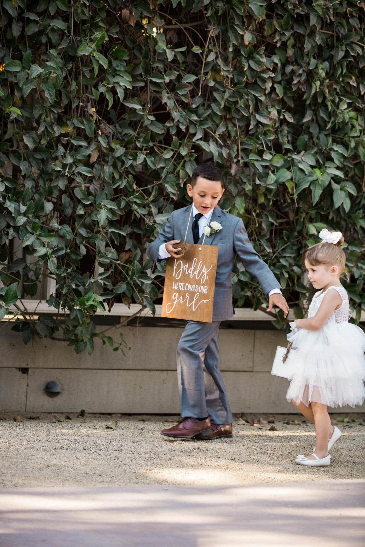 Ring bearer reaches for the flower girl's hand prior to walking down the aisle