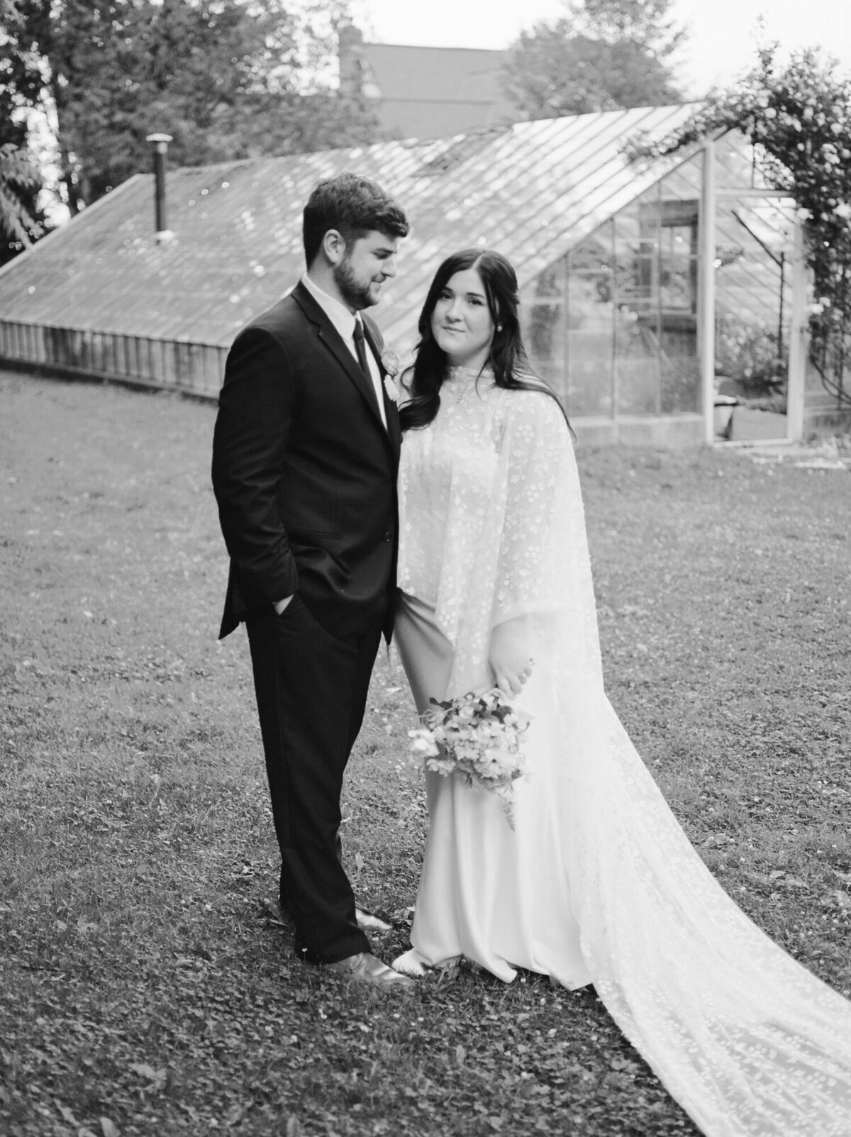 groom with bride, bridal cape at greenhouse wedding venue in Michigan
