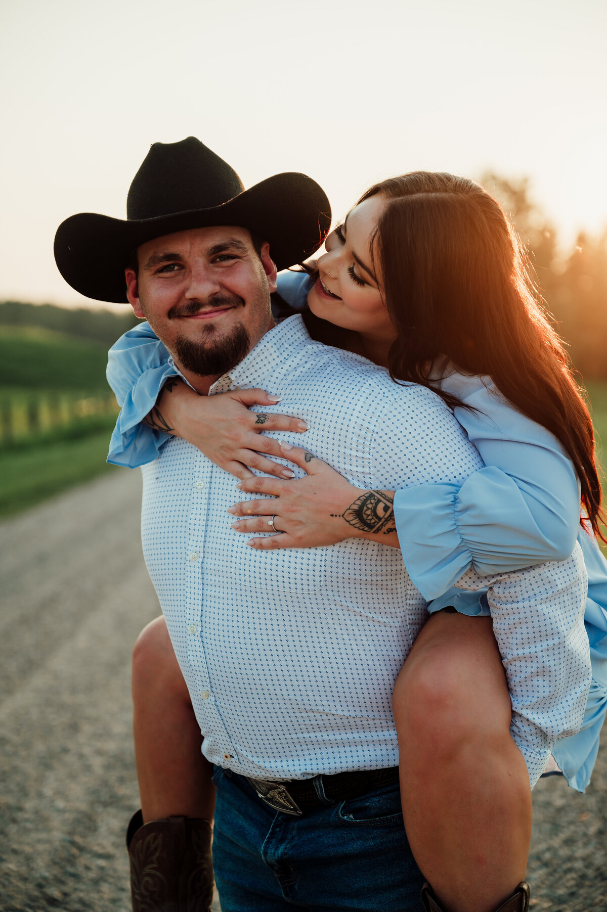 cowboy gives his wife a piggy back ride on dirt road near Edmonton, Alberta
