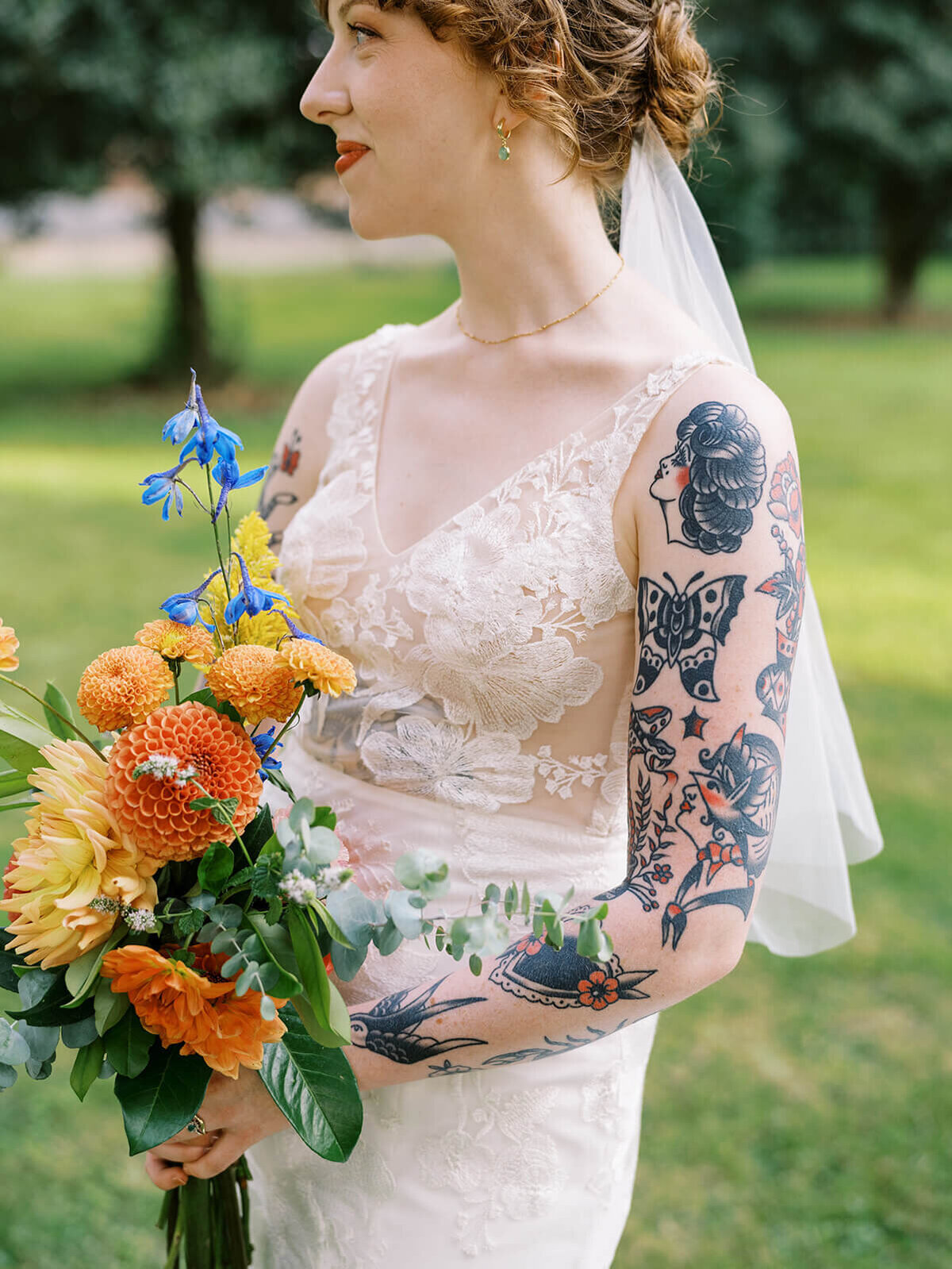 A faceless bride with tattoos holding her colorful bouquet. 