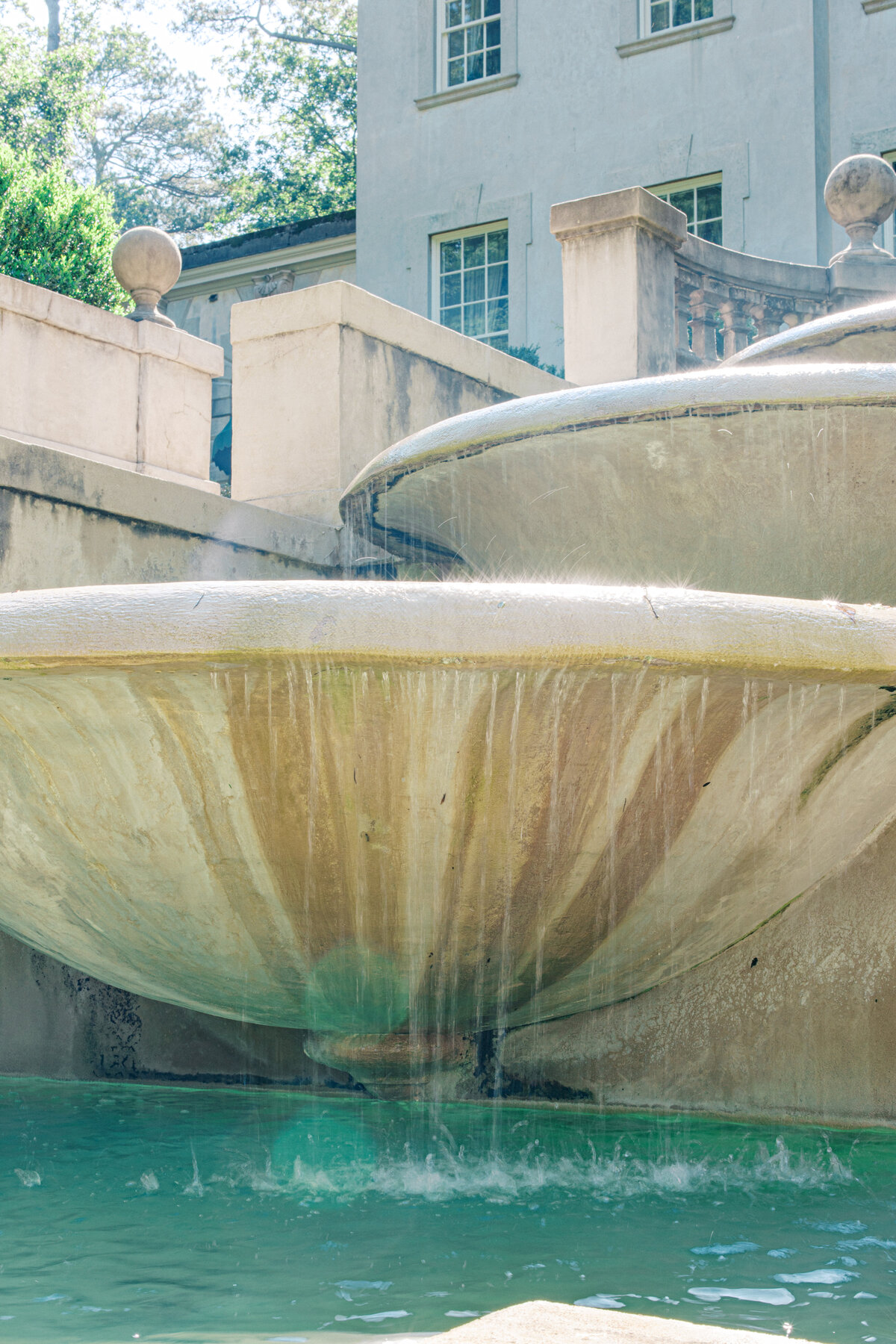 Water drips with sun sparkling down Swan House fountain 