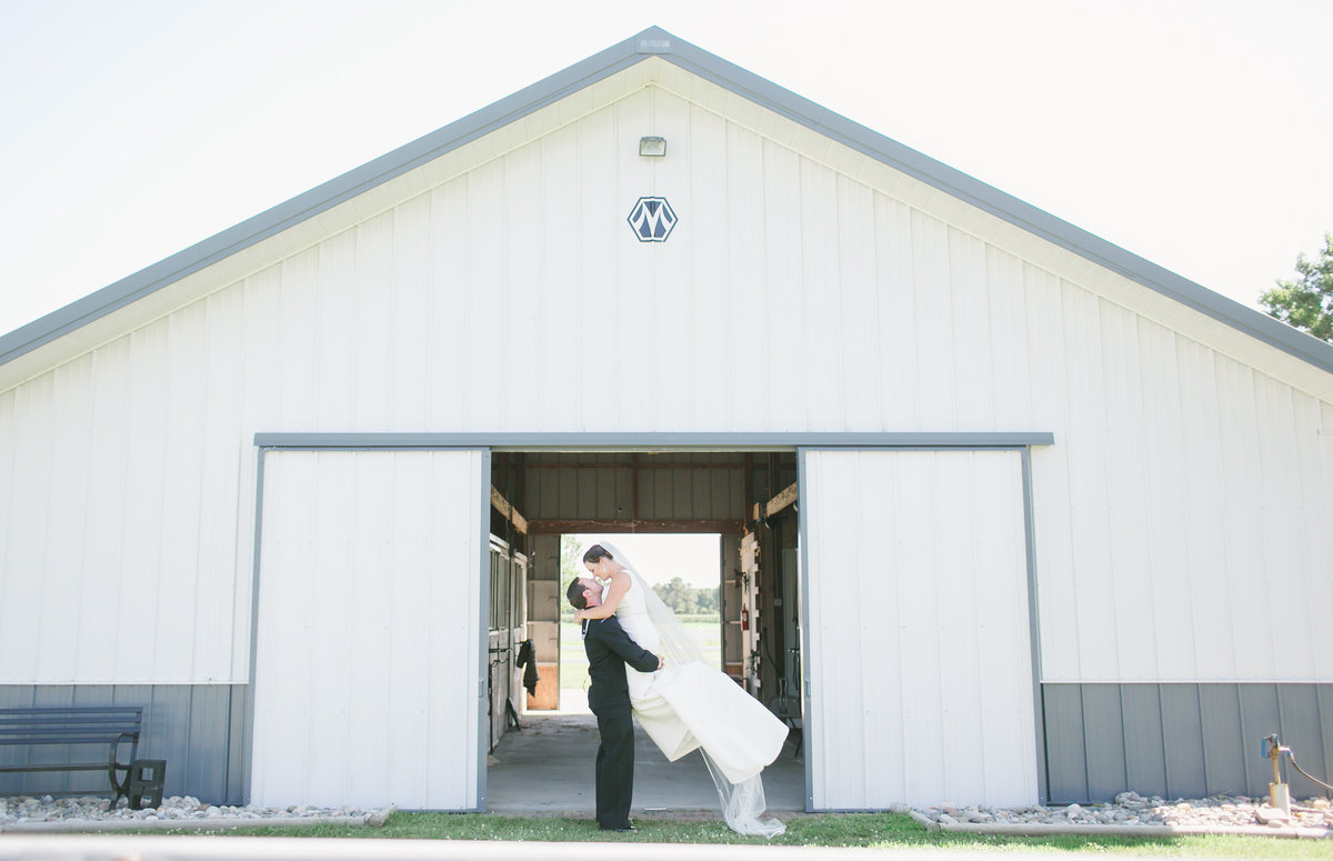 Bride & Groom pose in front of barn