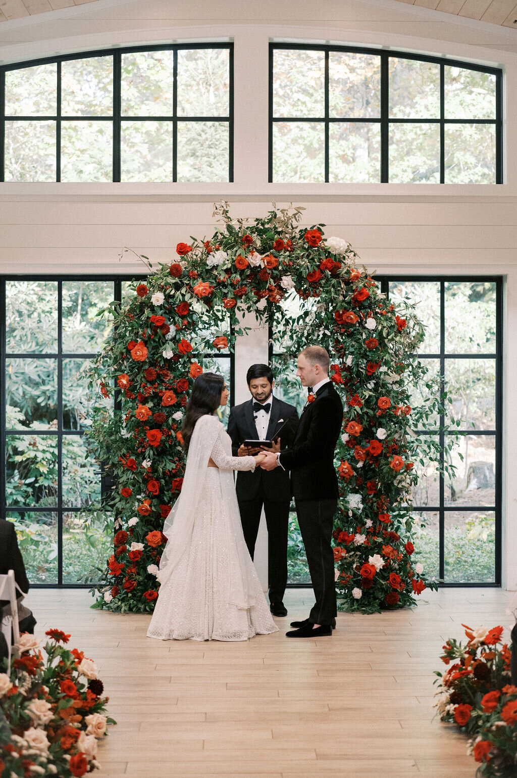 Bride and groom exchanging vows beneath floral arch during indoor ceremony at Old Edwards Inn in Highlands, North Carolina.