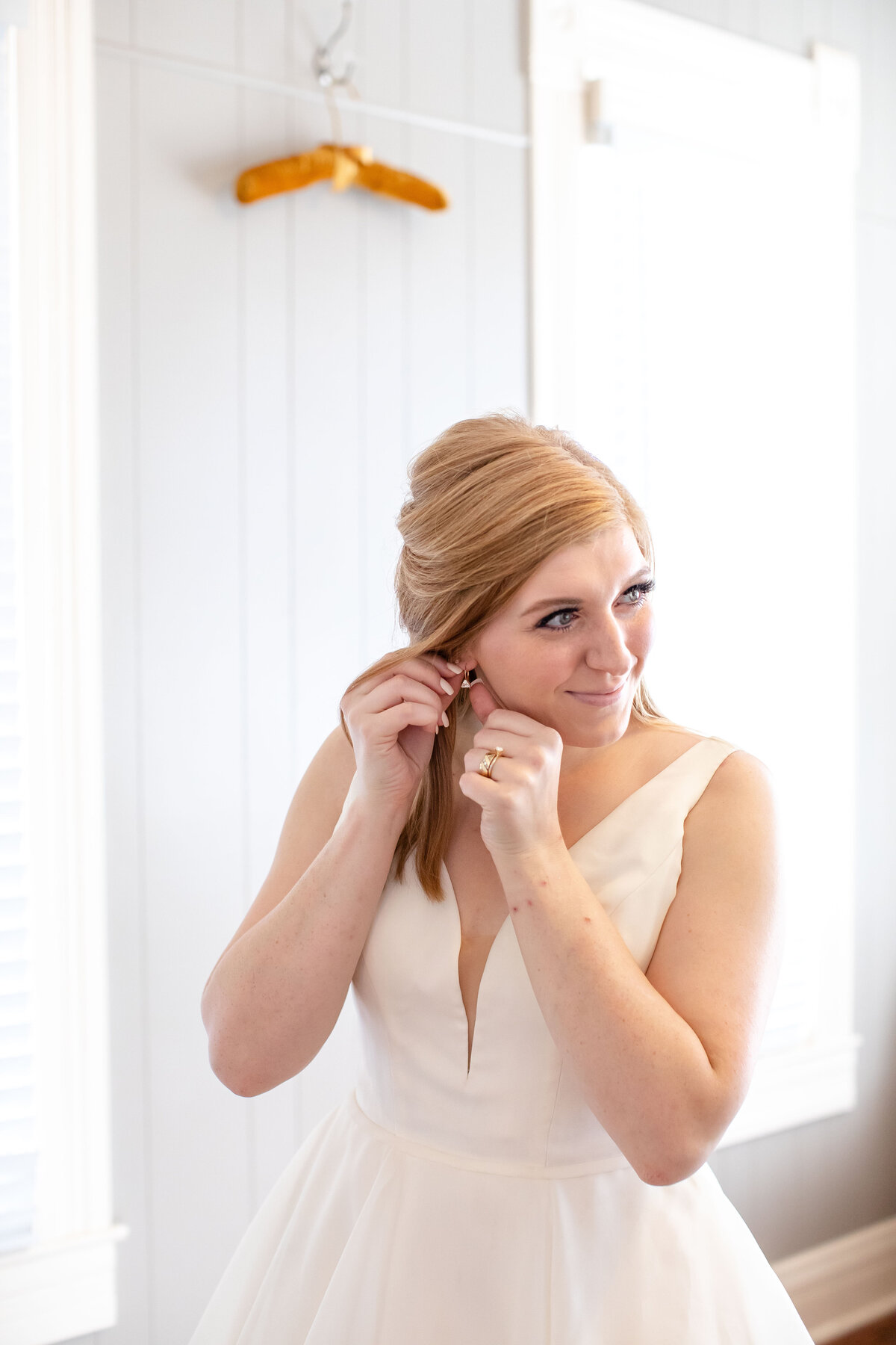 bride at Allen Farmhaus in New Braunfels Texas adjusts earrings