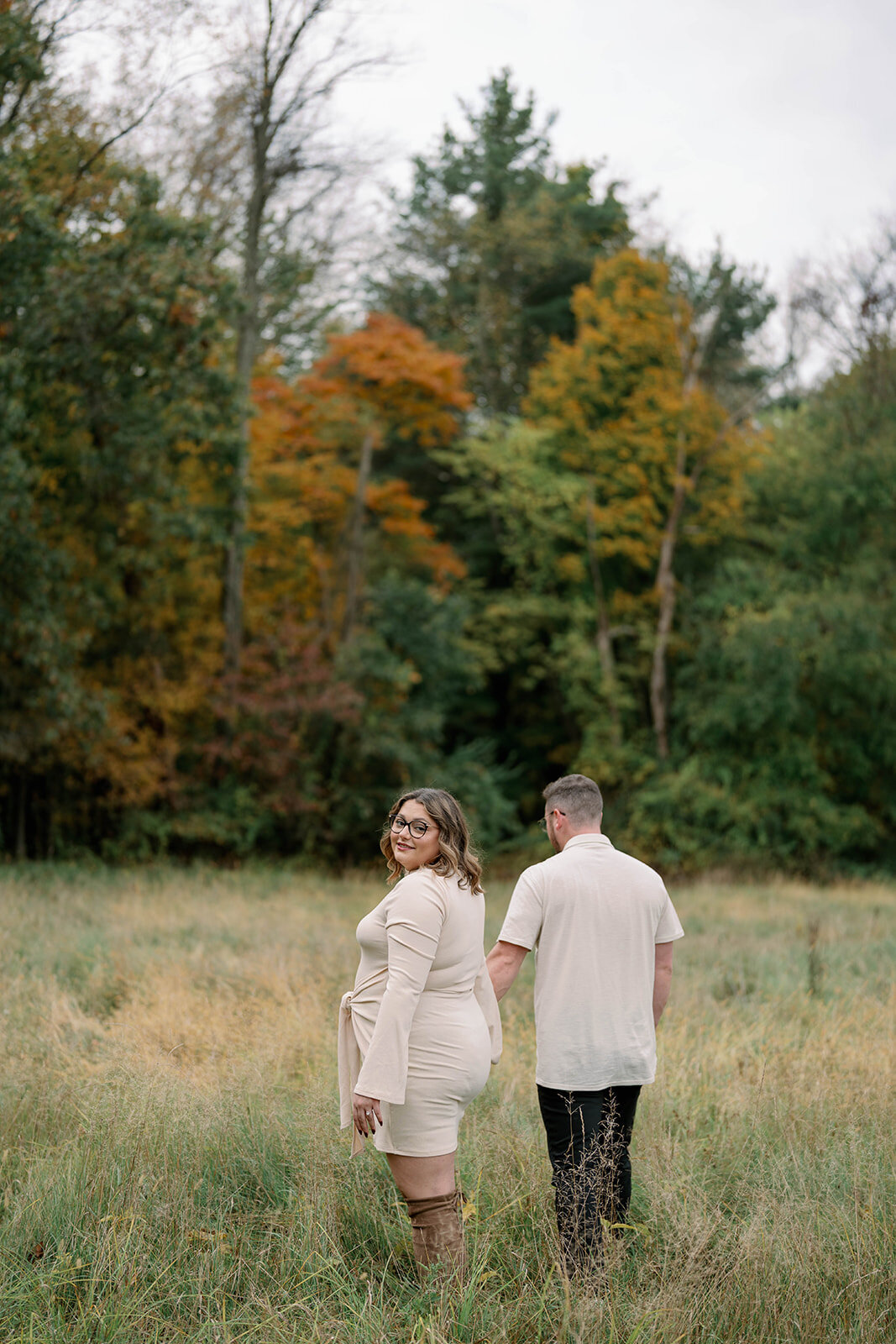 Couple walking away from the camera with golden fall trees behind them during their Al Sabo Preserve engagement photos.