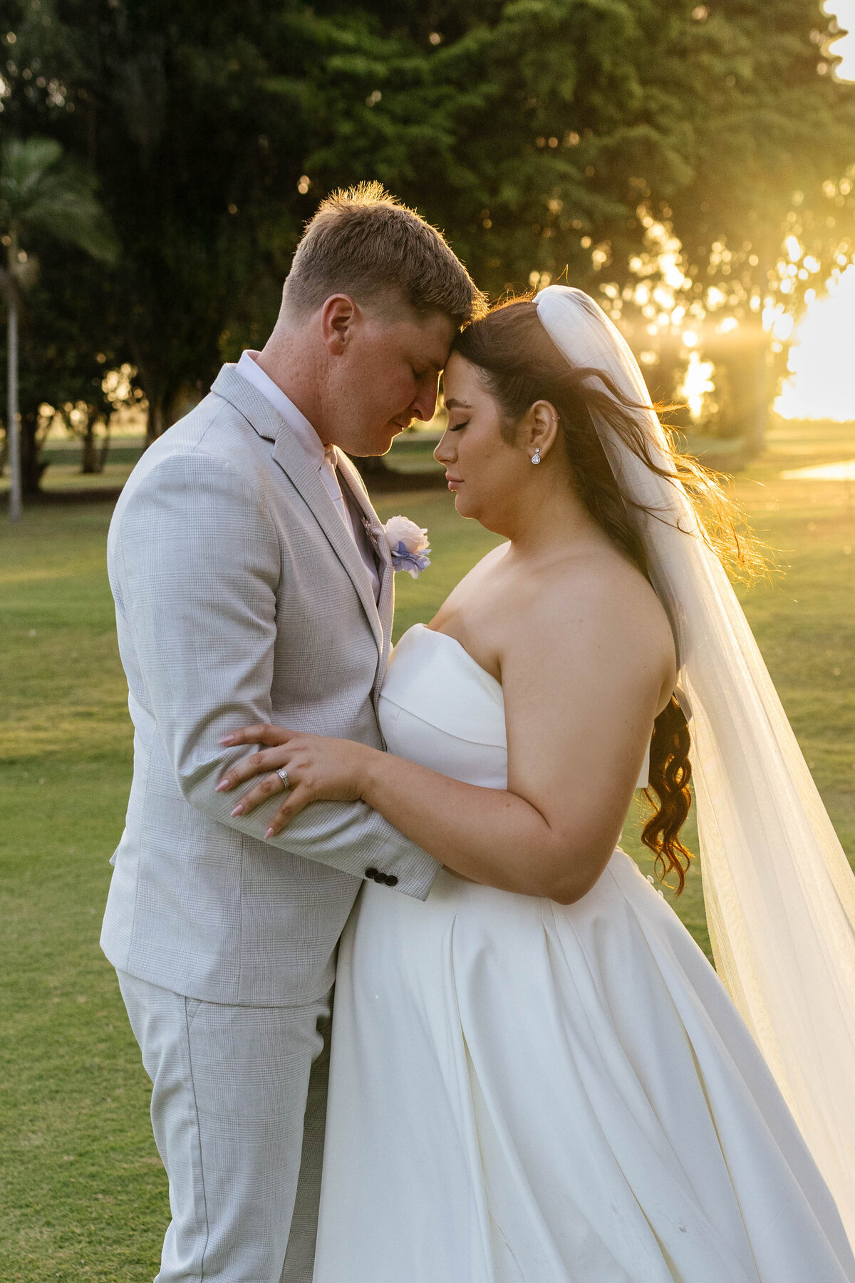 The bride and groom are standing chest to chest with their foreheads touching sharing a gentle moment. 