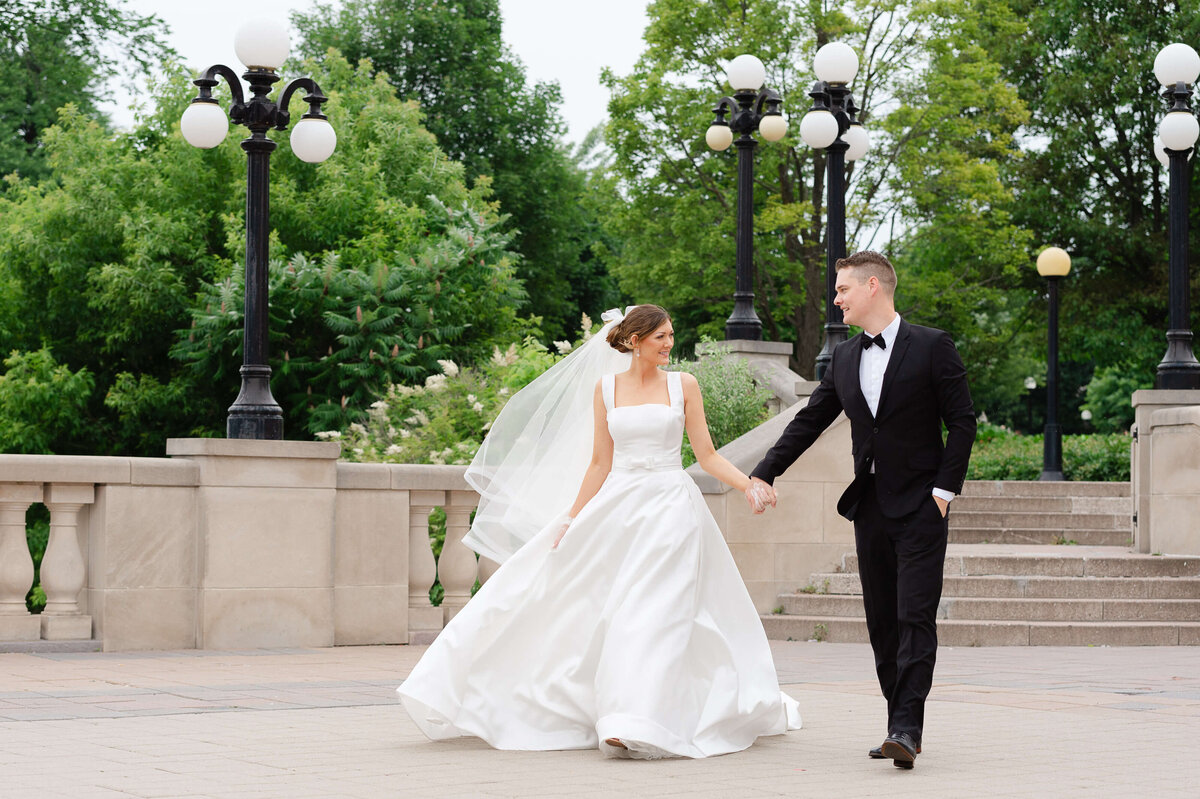 a bride and groom walk hand in hand on the terrace of the Chateau Laurier. Captured by Ottawa wedding photographer JEMMAN Photography
