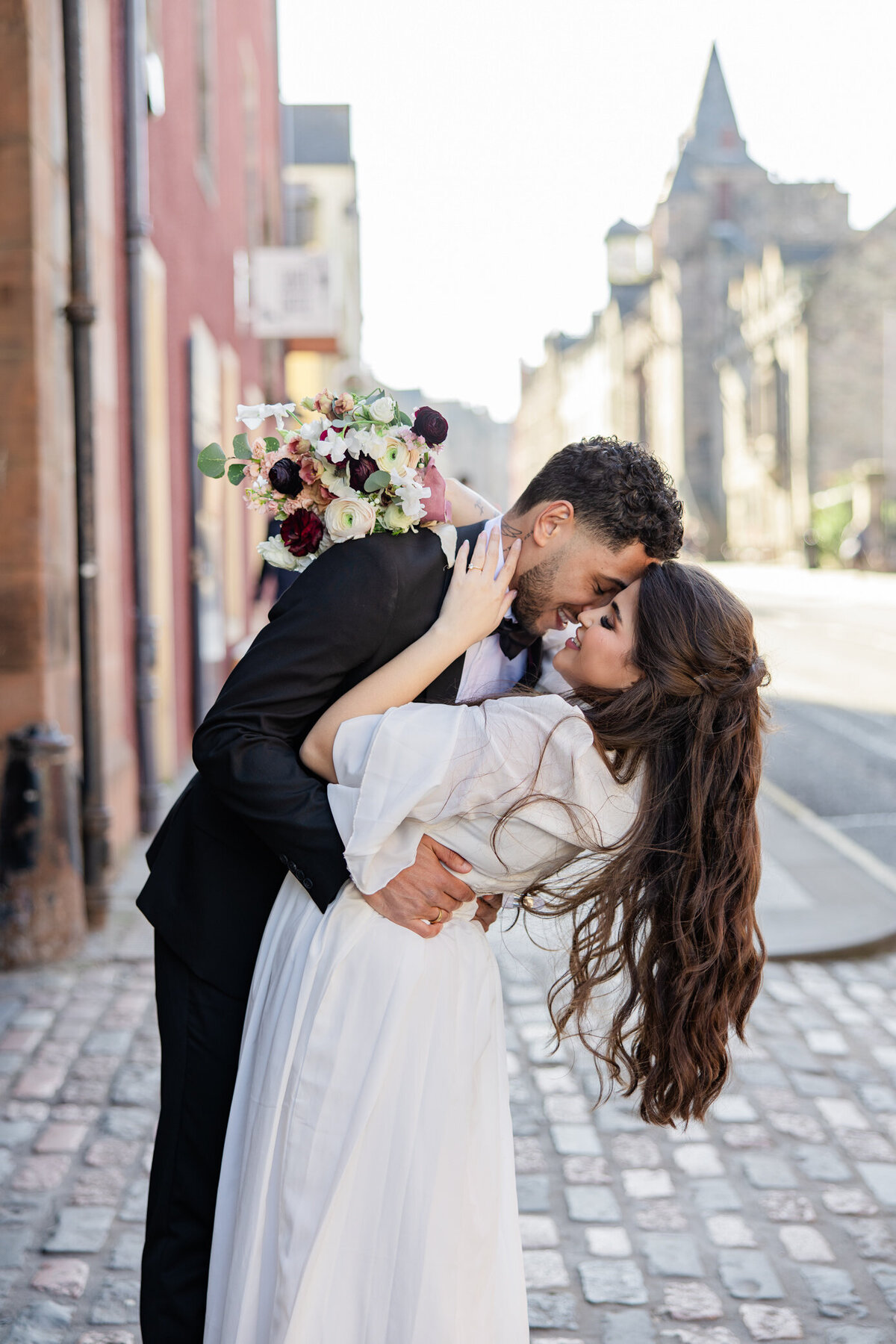 groom dips bride on a cobblestone street