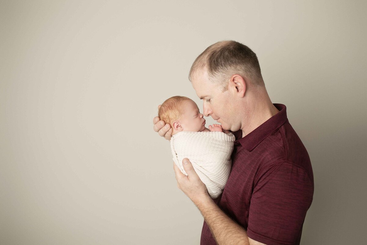 Proud dad holding his newborn baby boy, smiling with overwhelming love and joy