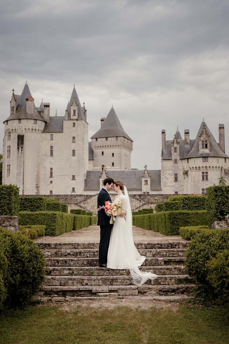 Couple anglais se tenant face à face dans les jardins d’un château du Coudray Montpensier dans la région de Tours, lors de leur mariage élégant et romantique.