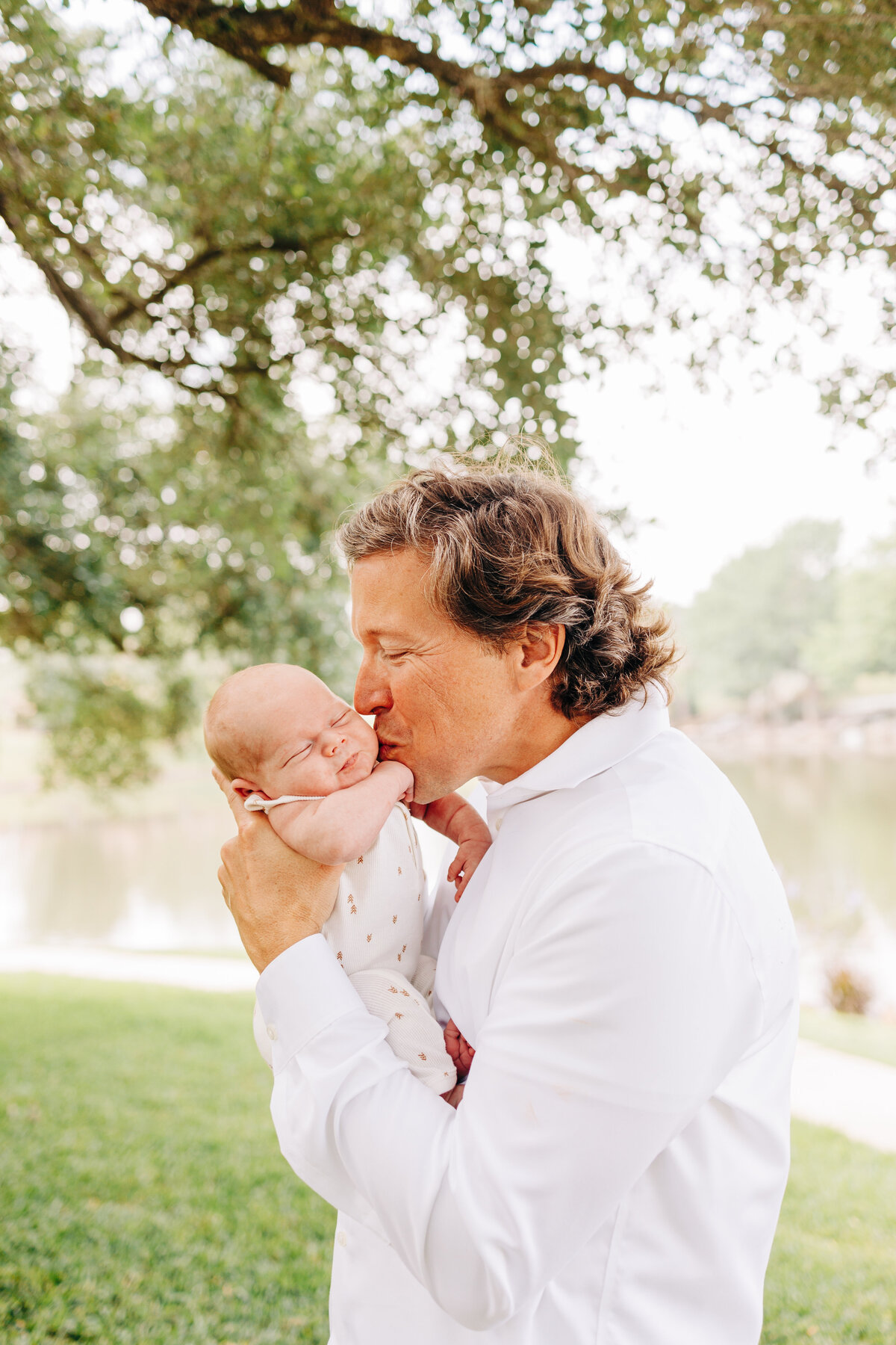 father kissing his newborn baby during his outdoor newborn session