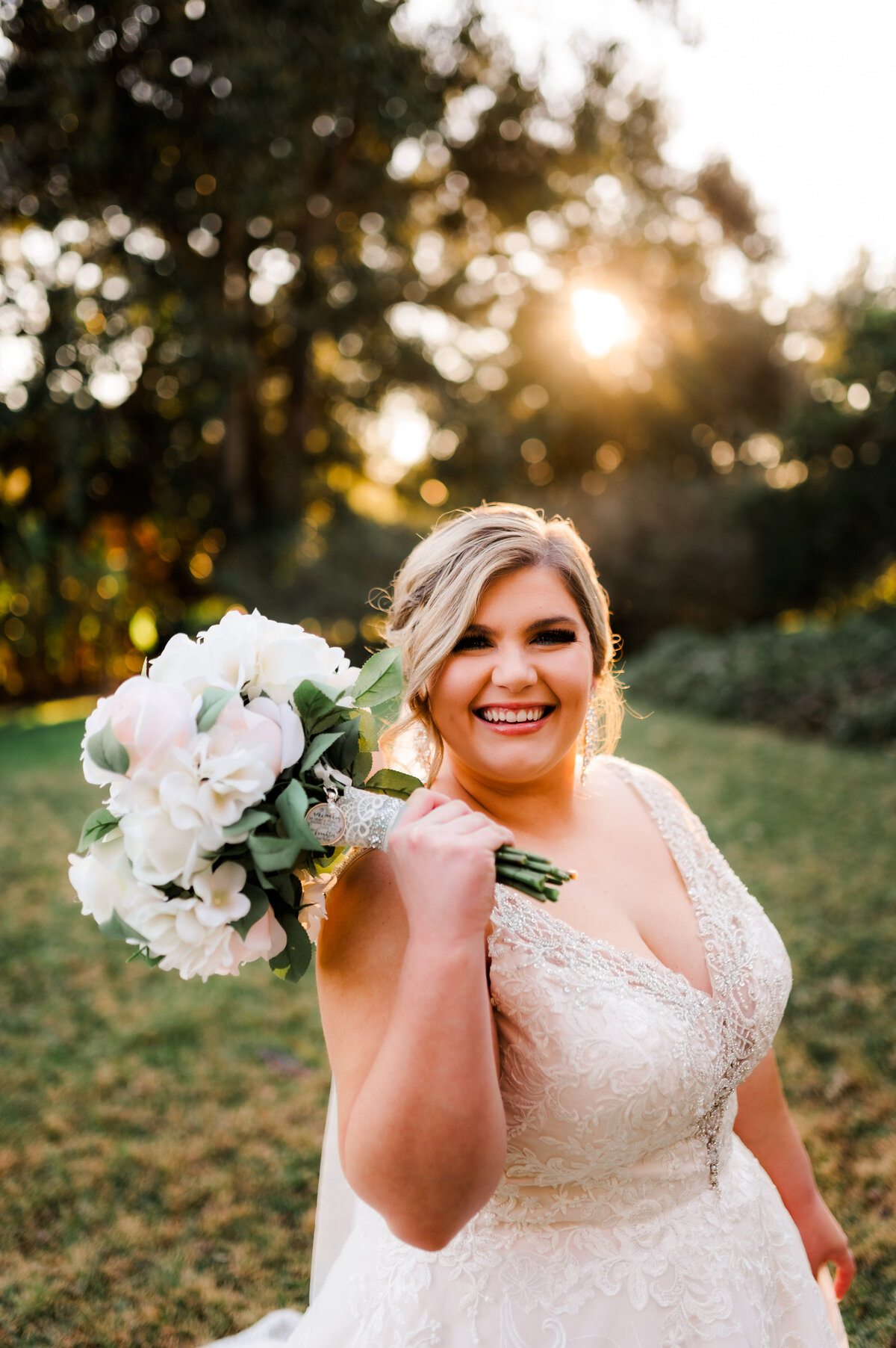 sun setting behind a bride as she laughs and holds her wedding florals up to her face in little rock ar