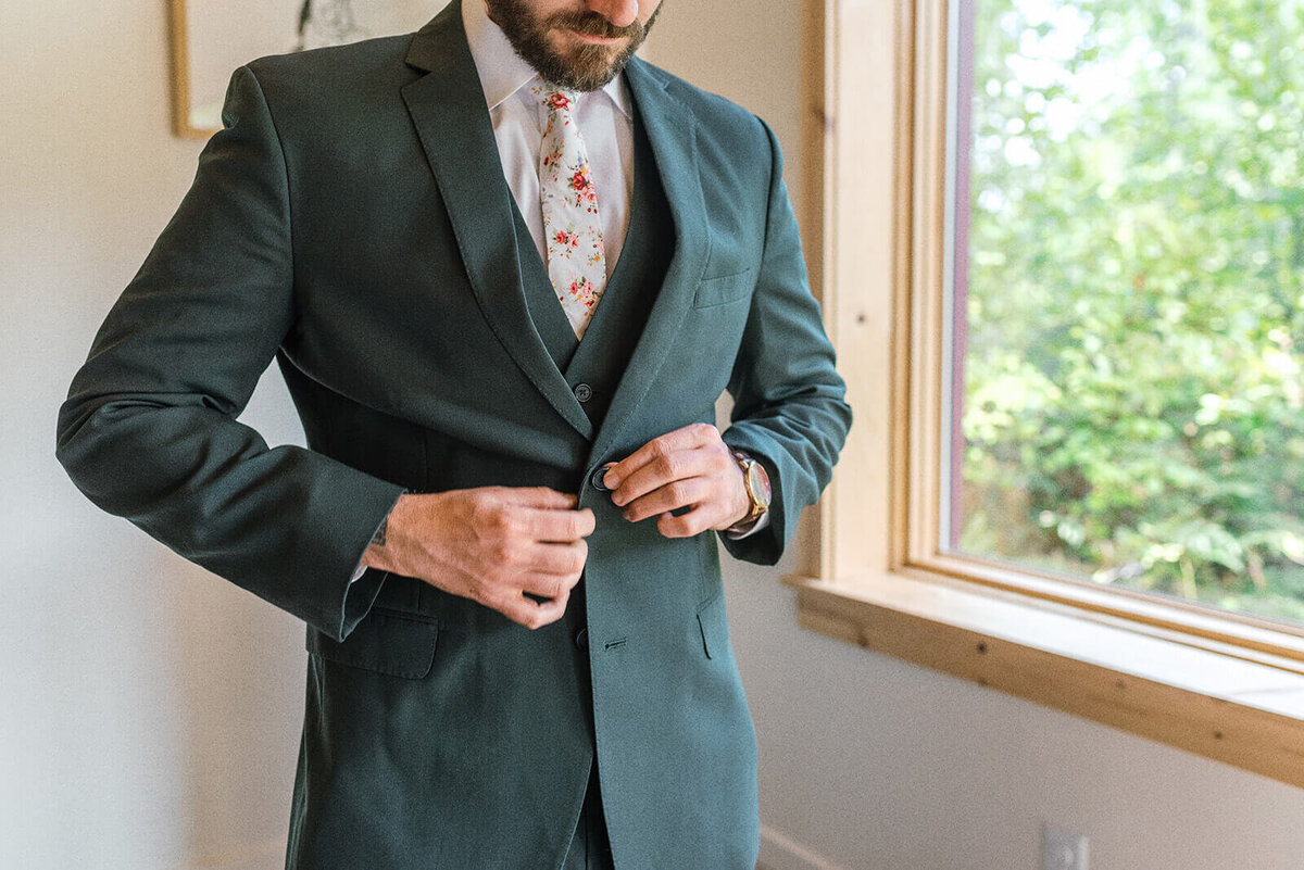 A man buttoning his suit before his outdoor wedding at Suttle Lake Lodge.