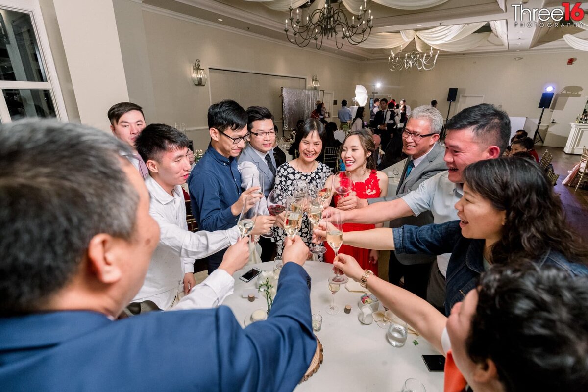 Bride and Groom share in a toast with wedding guests around a table