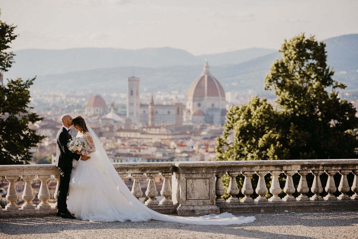 Bride and groom embracing with panoramic view of Florence Duomo from San Miniato al Monte, wedding photographer Tuscany.