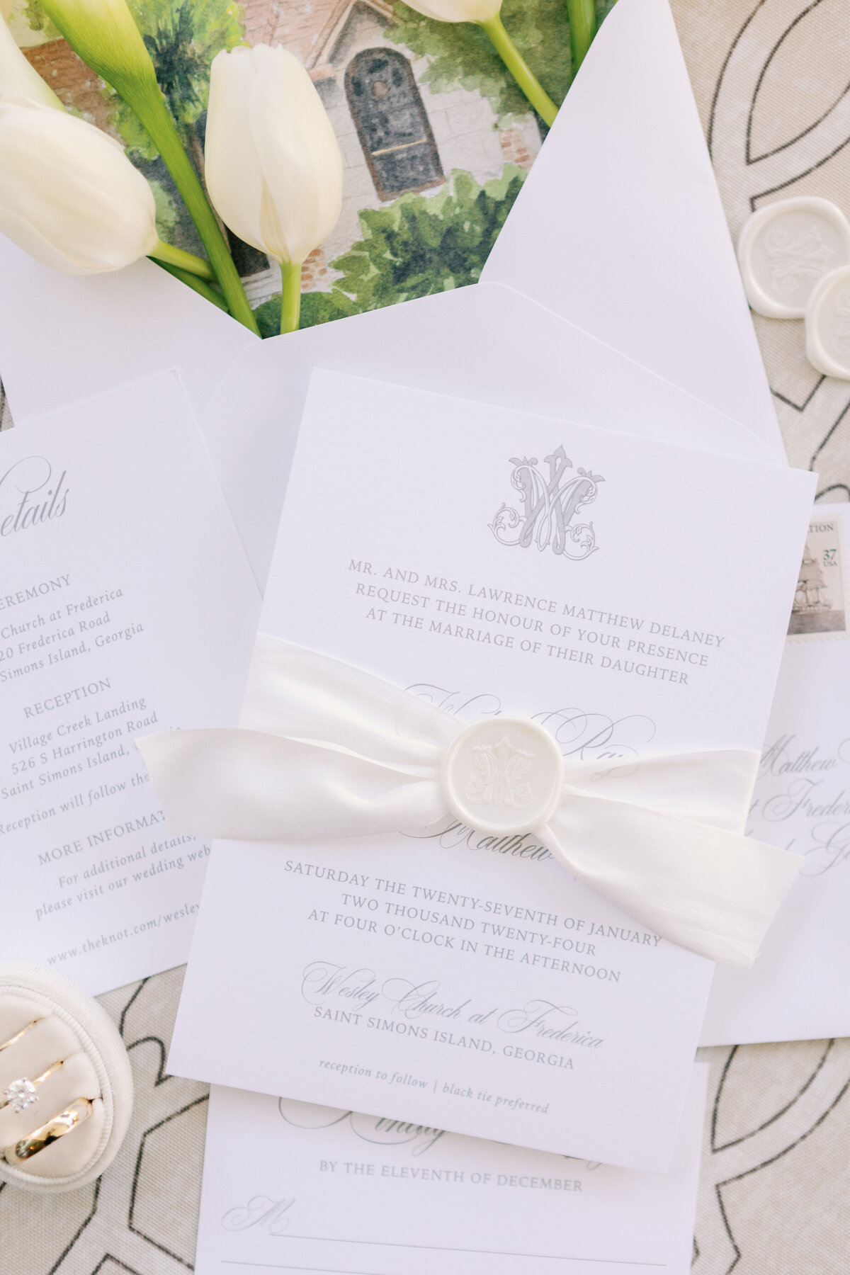sophisticated wedding invitations wrapped in a white ribbon closed with a wax seal