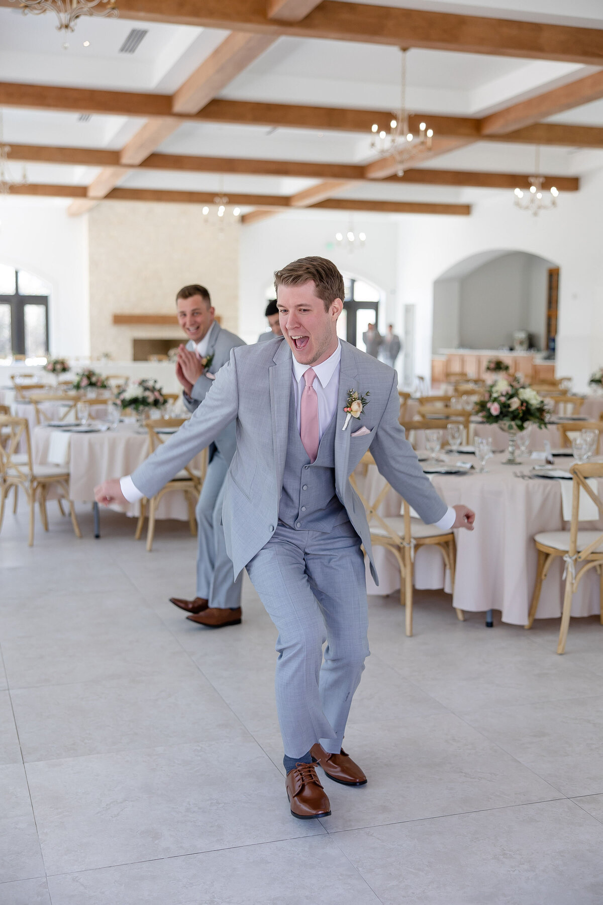 groomsman dances through reception room at The Preserve at Canyon Lake Texas wedding with pink tie