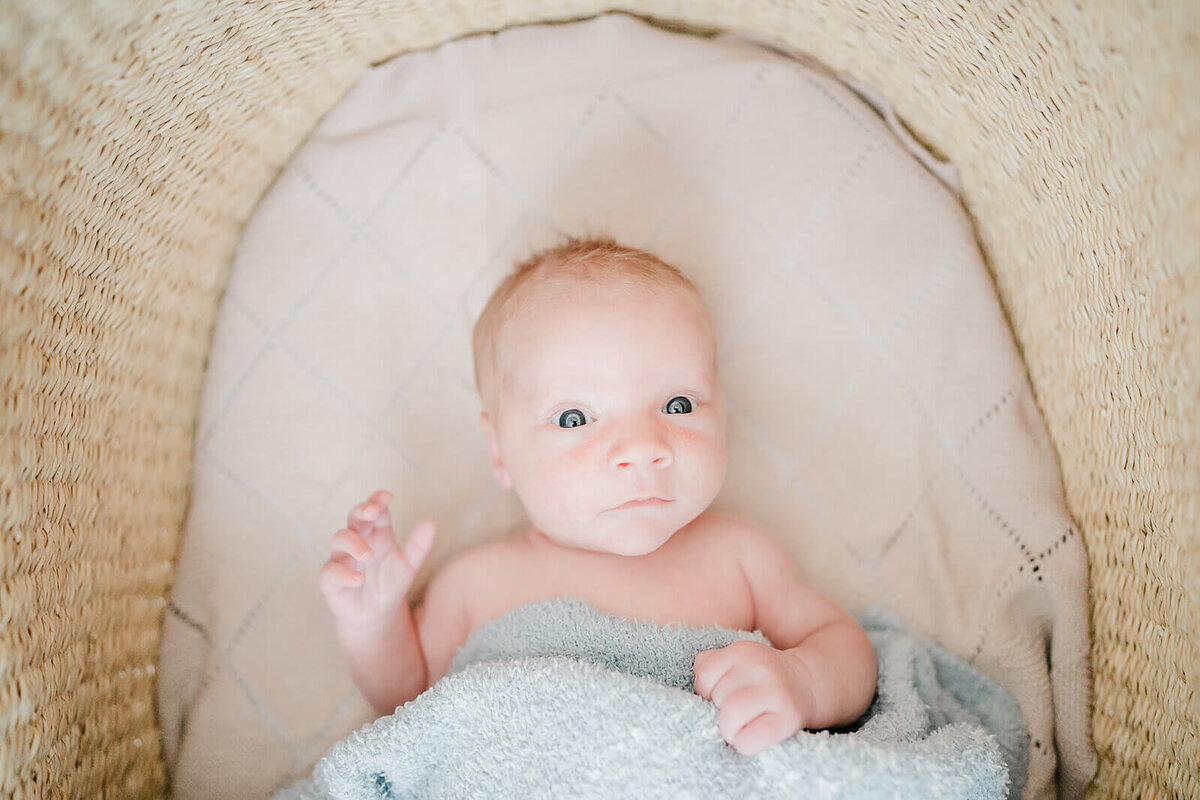 Natural light newborn portraits in Bay Area bedroom with soft beige tones.