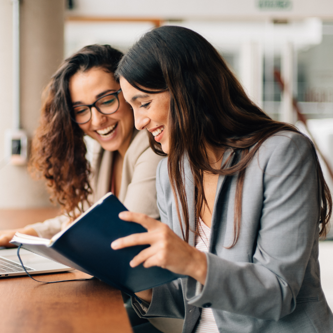 two women laughing and working together