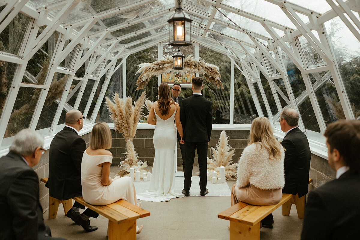 Elegant indoor wedding ceremony at The Greenhouse, a unique garden wedding venue in Abbotsford, BC, featured on the Brontë Bride Vendor Guide.