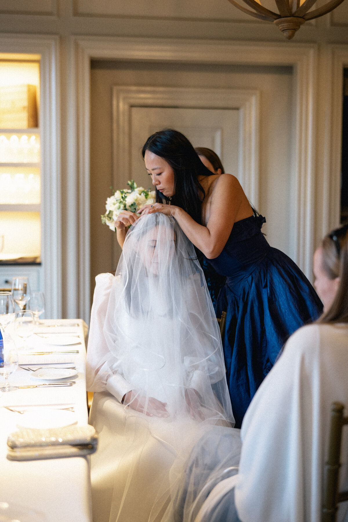 Bridesmaid adjusting bride’s veil before Cleveland wedding ceremony