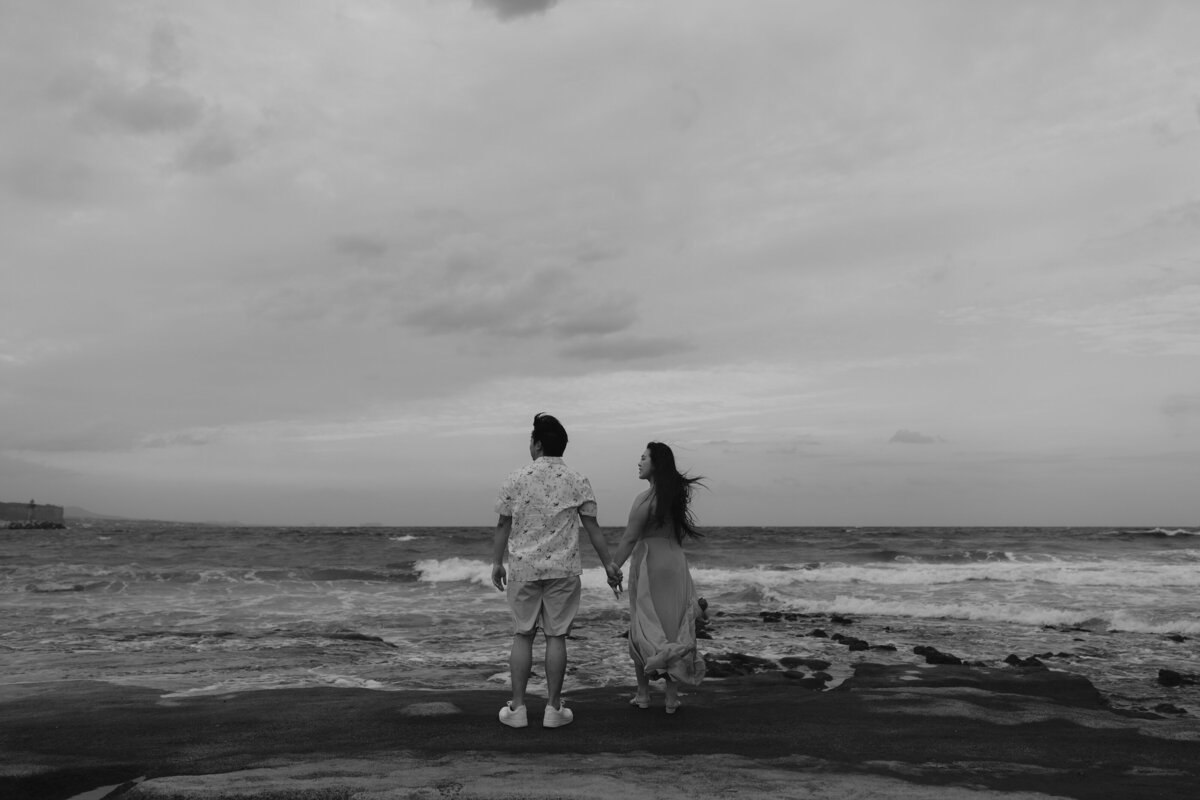 couple standing while holding hands and looking at the sea of jeju island