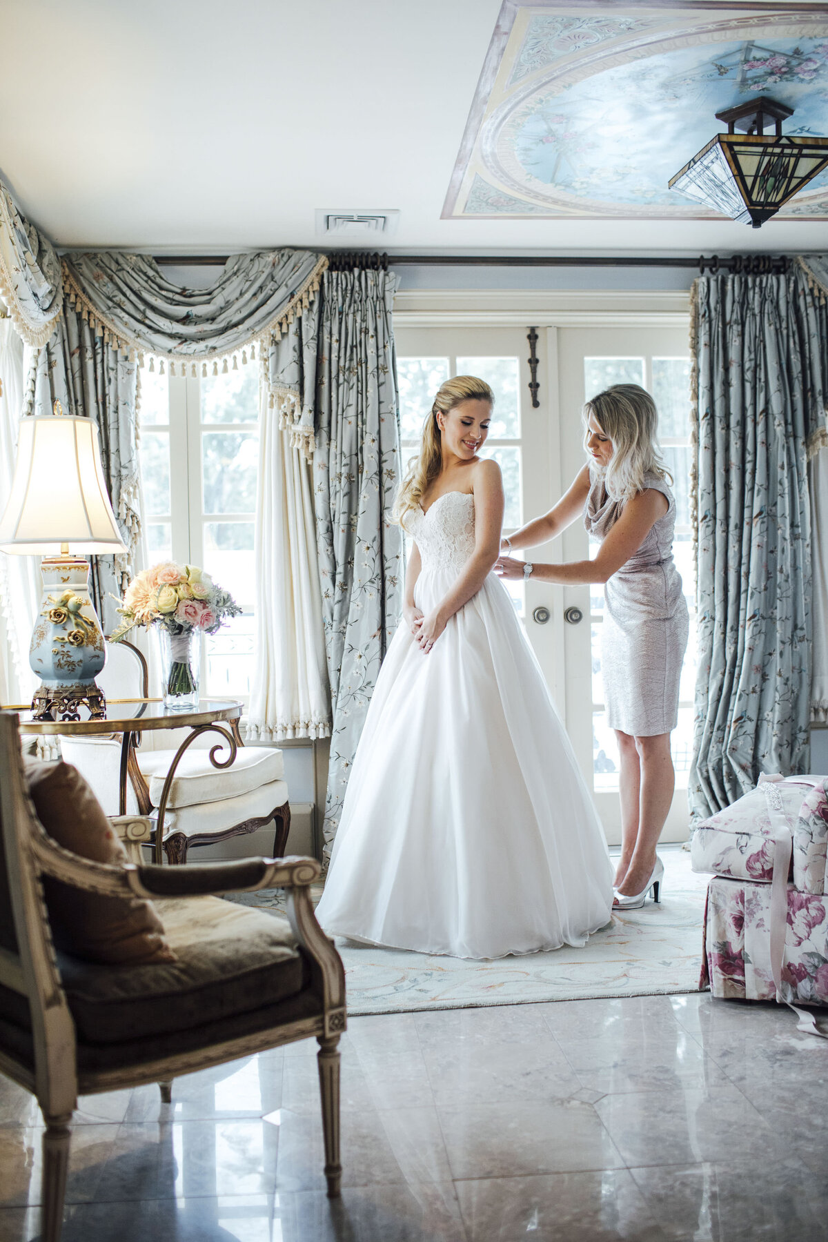 the-inn-at-barley-sheaf-bride-getting-into-dress-with-sister-bridal-suite-holicong-pennsylvania
