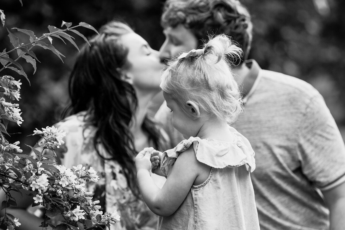 black and white maternity shoot with sibling. Parents kissing