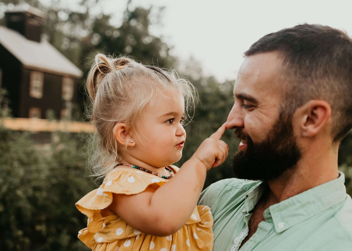 A bearded man and a little girl posing in front of a farm, captured by a Pittsburgh family photographer.