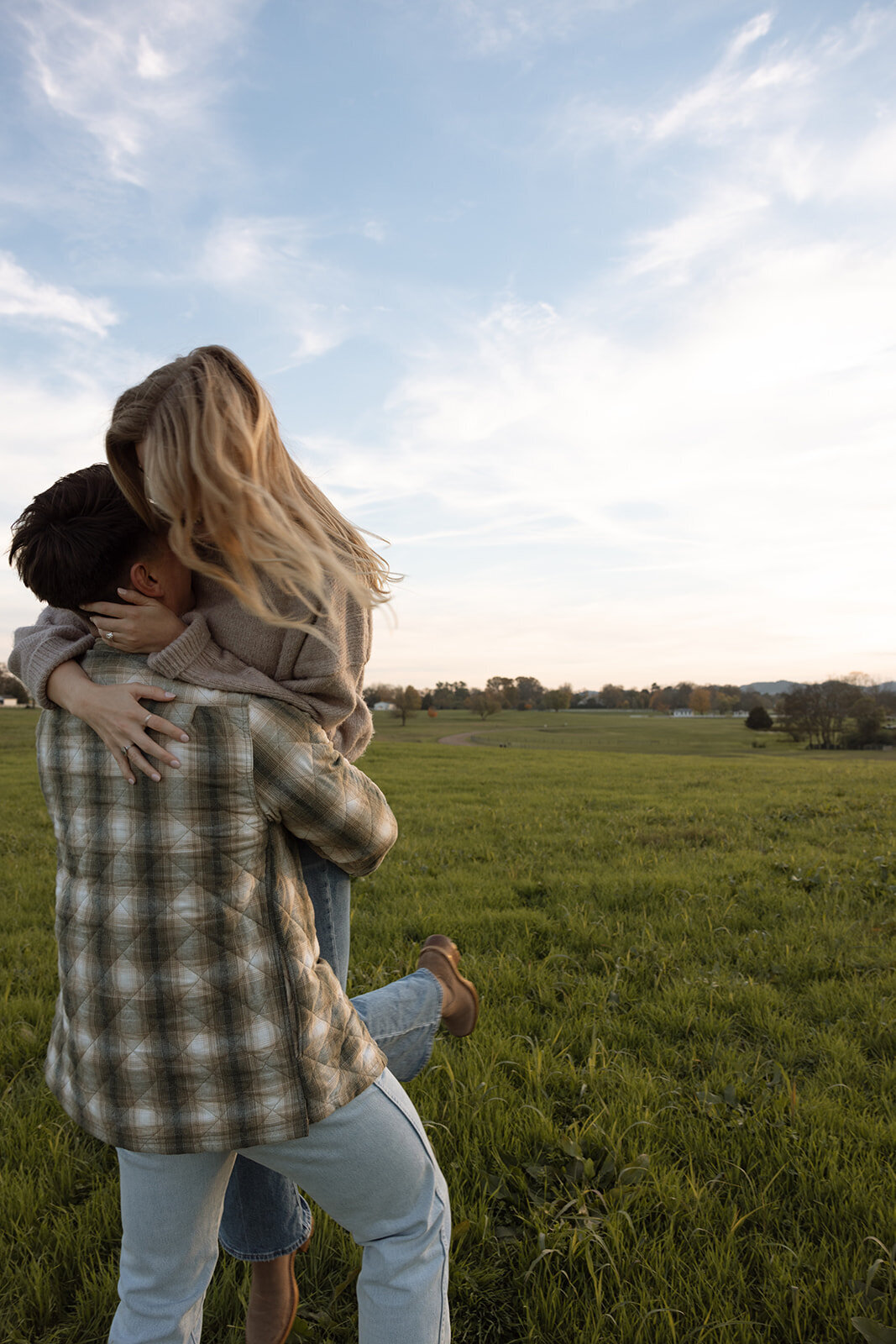 Couple laughs as he lifts her and twirls her in the air. 