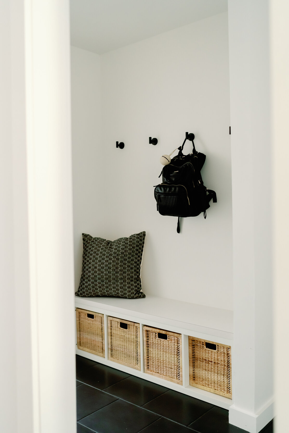 hallway storage built in with hooks and black tile floor