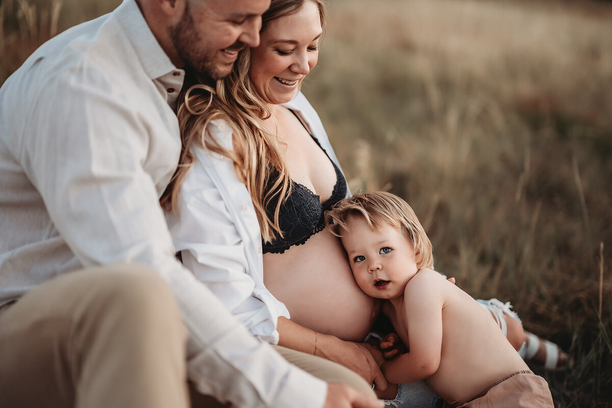 boy with his ear to mom's bare pregnant belly