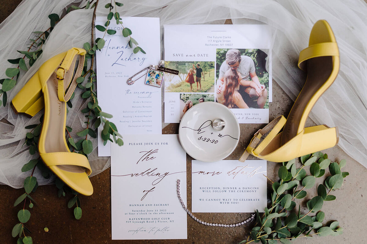 Flat lay of wedding invitations and shoes with rings