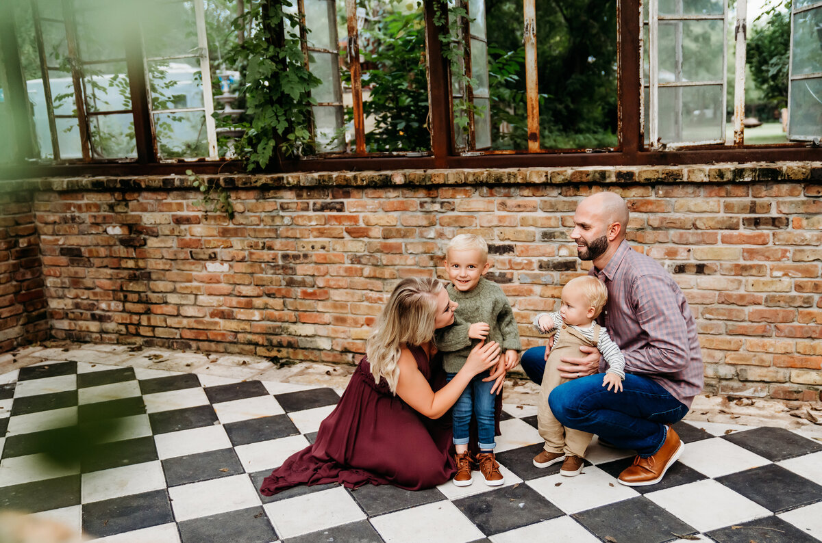 Family Photography, Mom and dad huddle with their two young sons in a green house