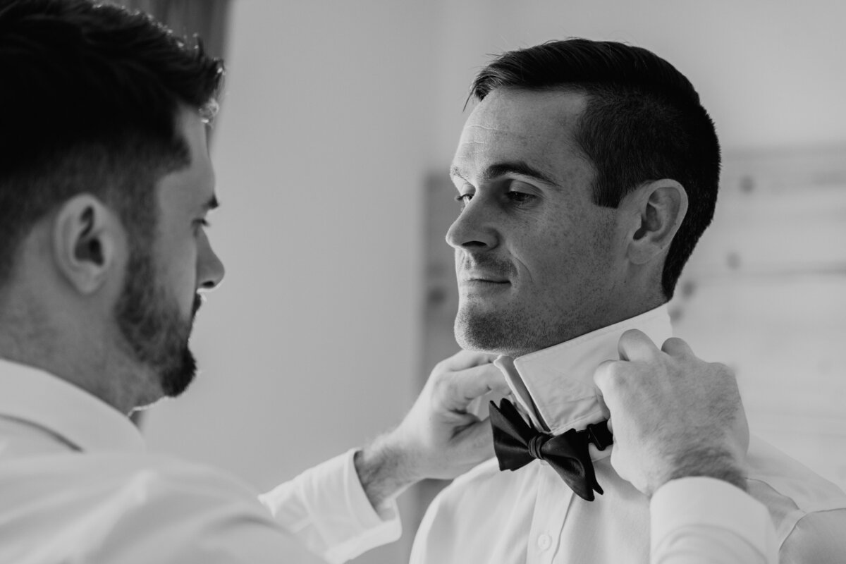 Groom adjusting bow tie before ceremony