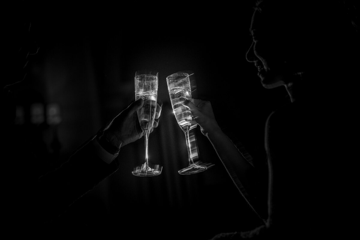 A couple reaching out champagne glasses towards each other.