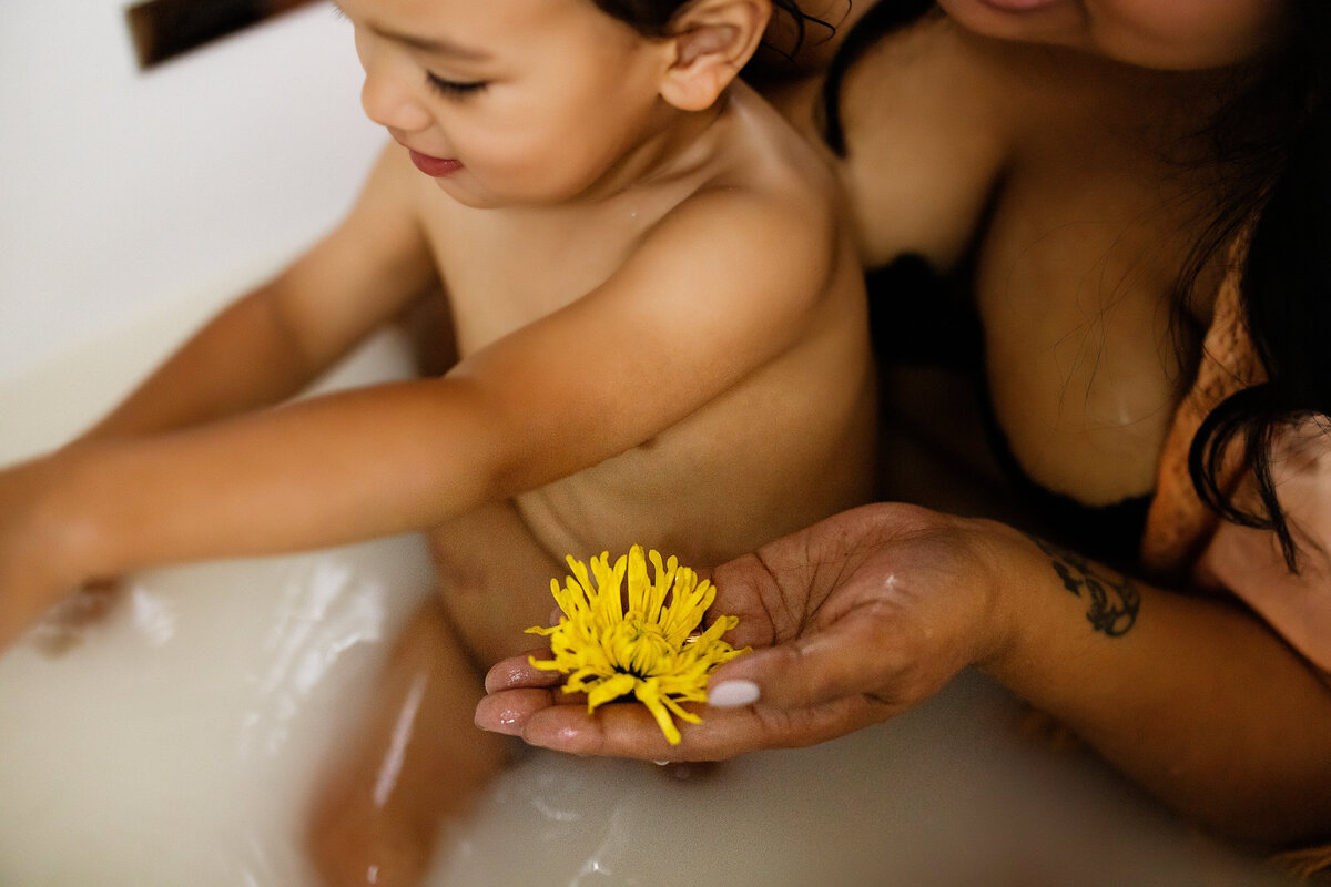 mother showing son flowers in milk bath