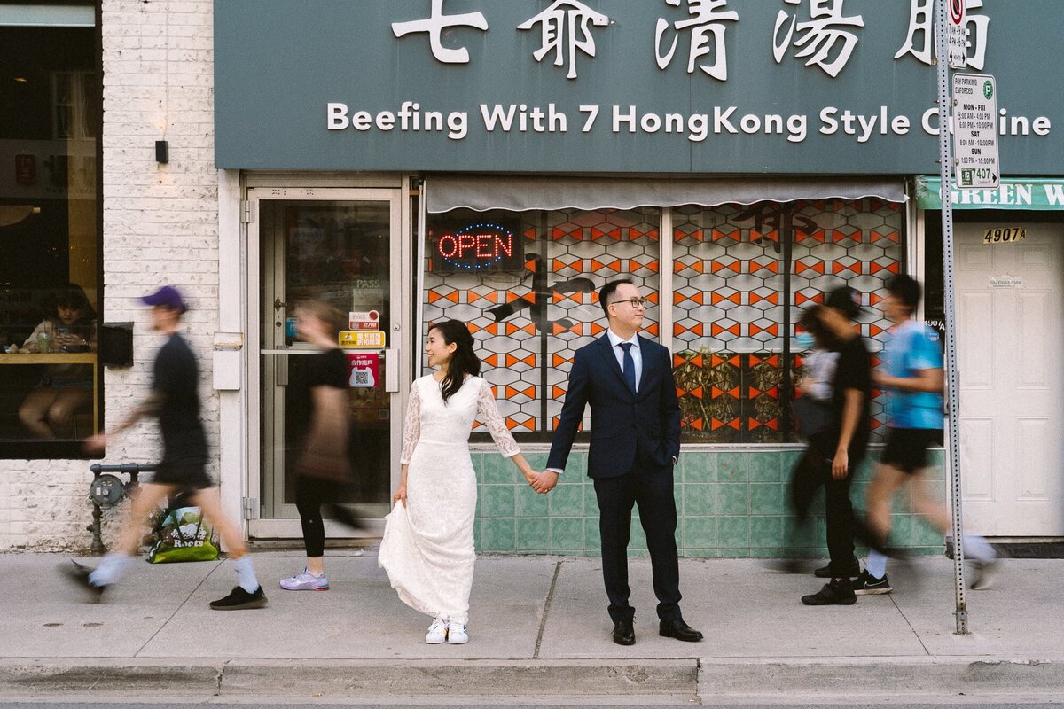 bride and groom standing outside restaurant holding hands