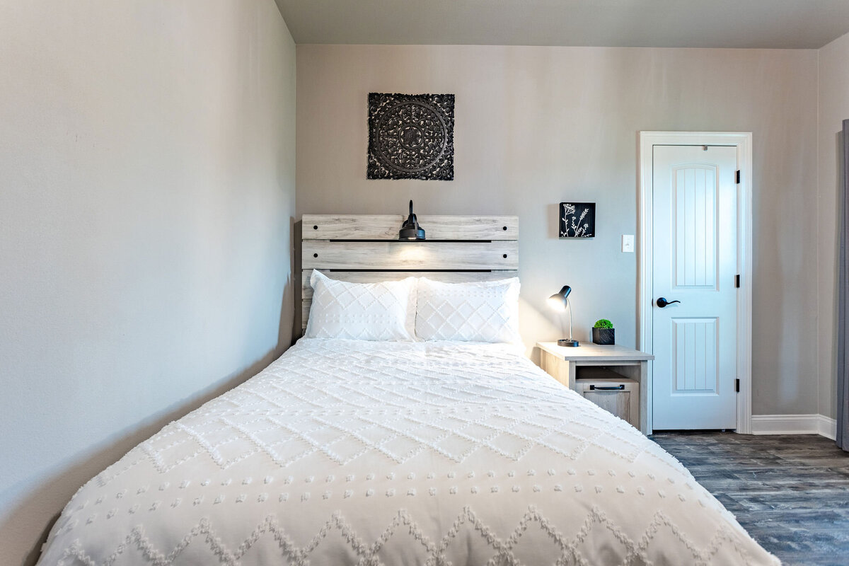 Bedroom with comfortable bedding in this five-bedroom, 3-bathroom vacation rental house for up to 10 guests with free wifi, private parking, outdoor games and seating, and bbq grill on 2 acres of land near Waco, TX.