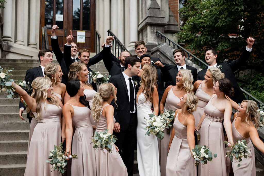 Summer Nashville wedding featuring the full bridal party carrying white and greenery flowers