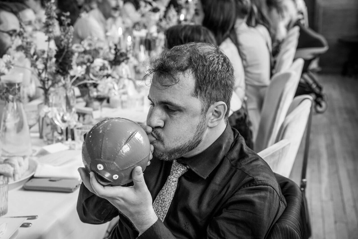 Funny photo man blowing balloon at wedding reception at The Town Hall Hotel London