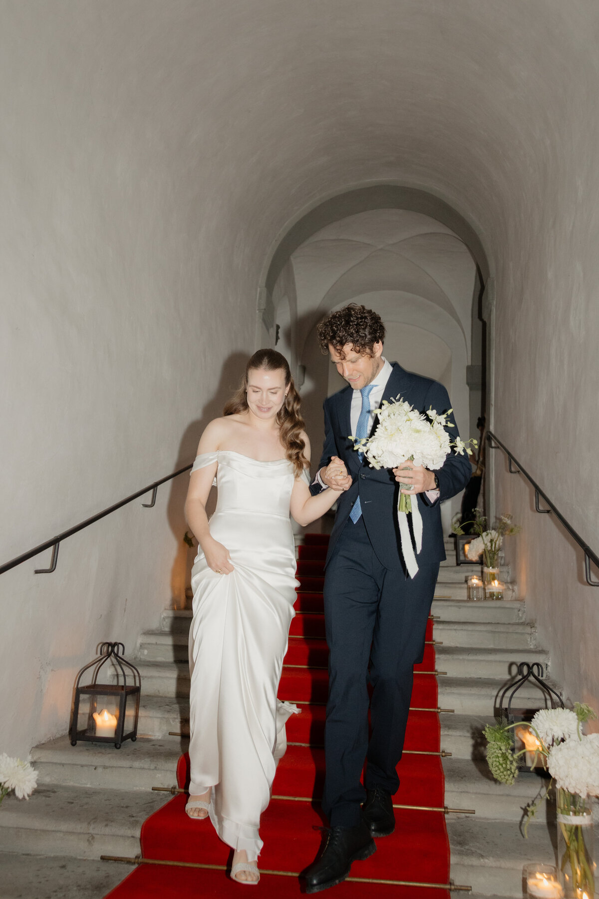 Brautpaar auf der Treppe mit roten Teppich – eleganter Empfang bei der Hochzeit im Palast Hohenems.

