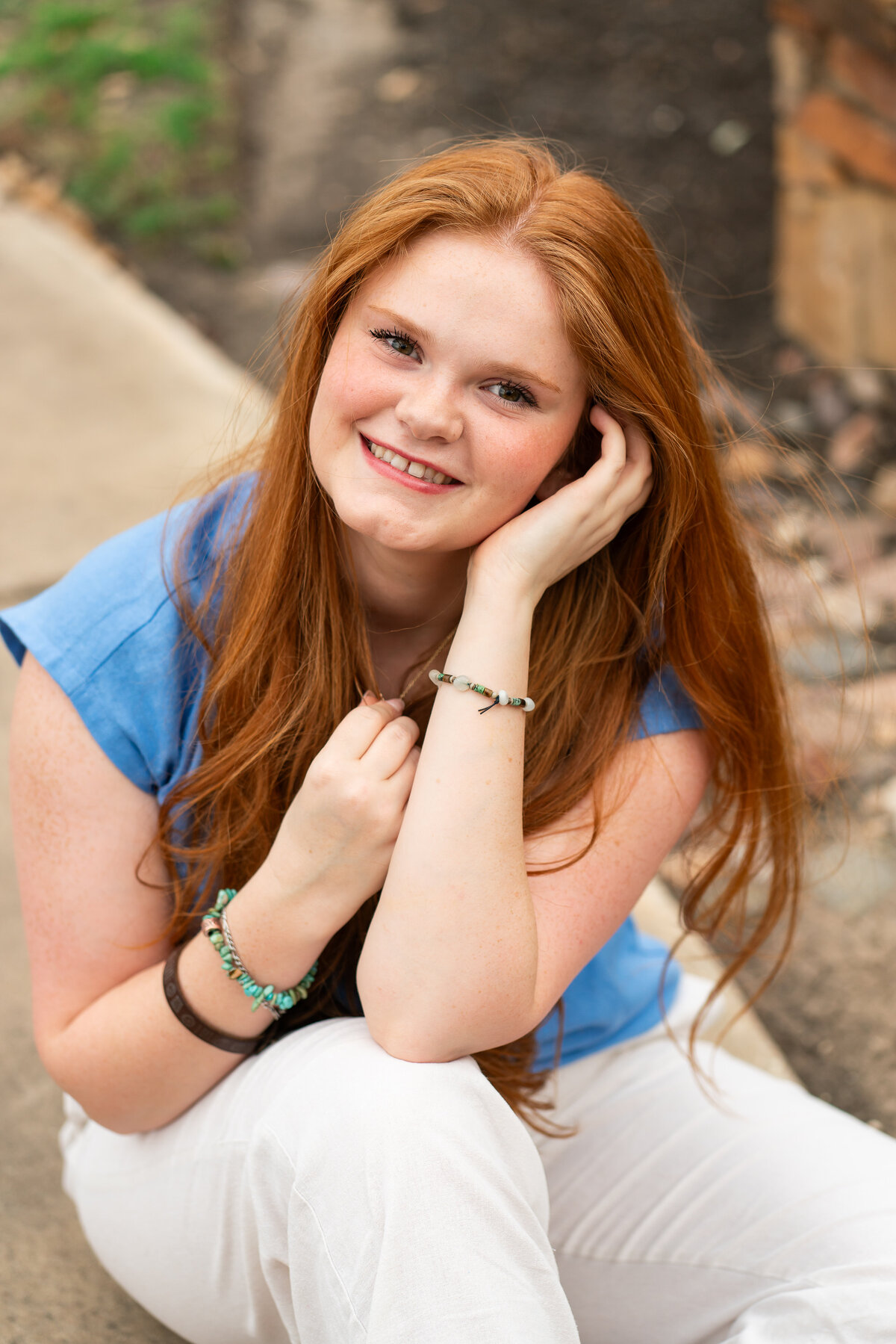 Red head high school senior girl posing in flowers for graduation photos. Austin Senior Graduation.