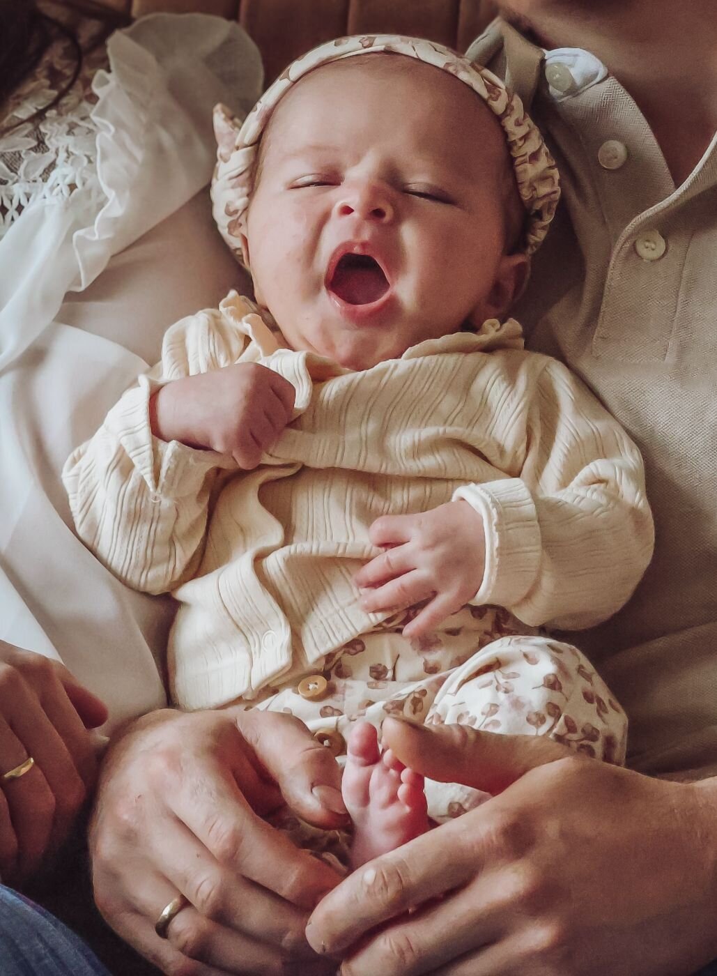 babymeisje gaapt terwijl haar vader haar vasthoudt 