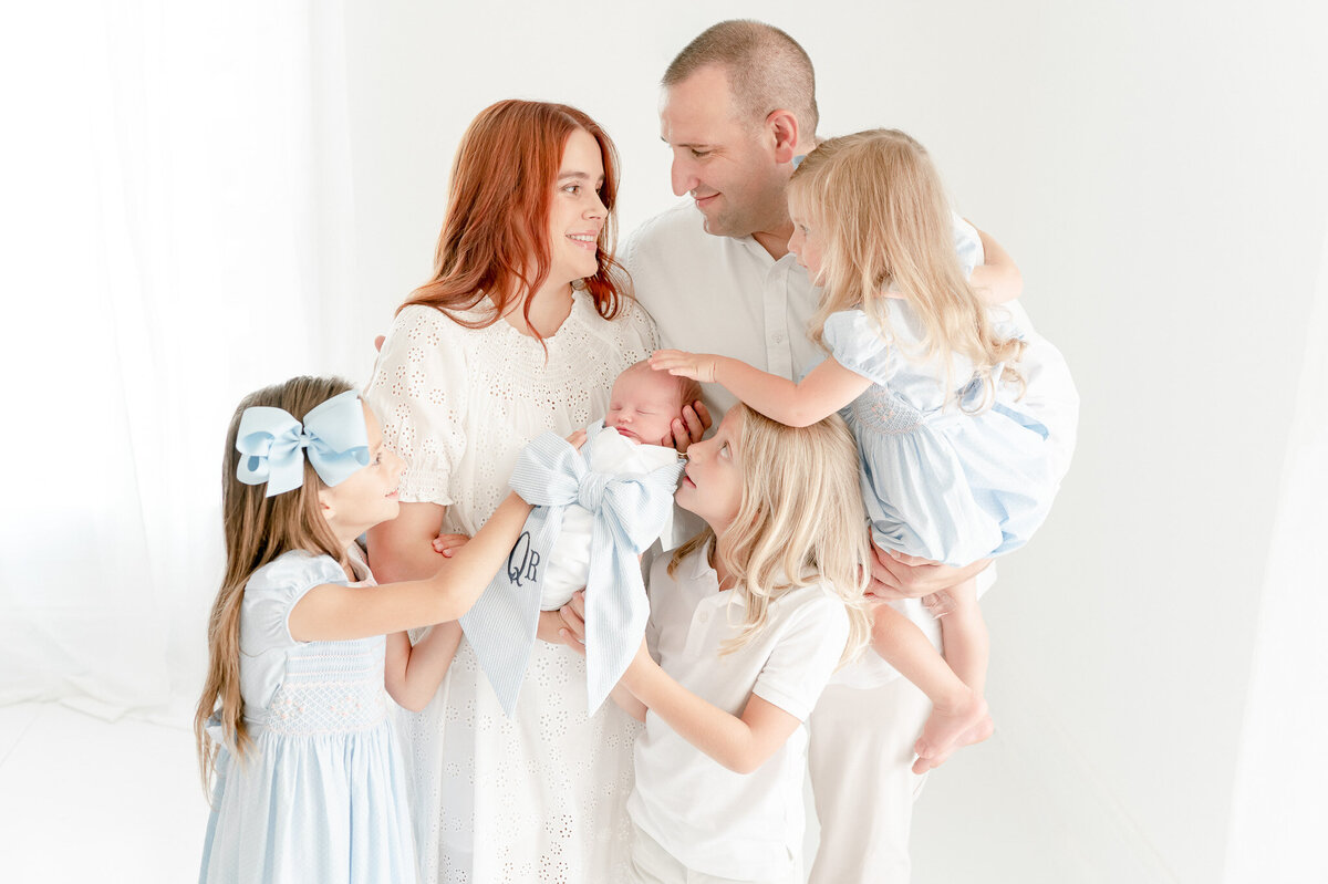 family with 4 children smile at each other In Kristie Lloyd’s Nashville newborn photographer studio