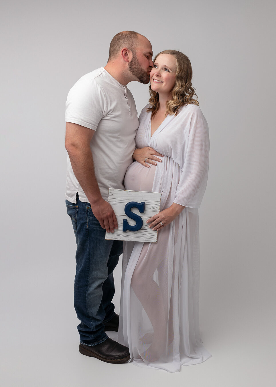 husband kissing his pregnant wife during studio maternity session