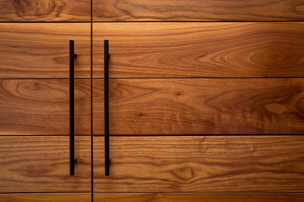 close up of dark wood cabinet doors with black handles