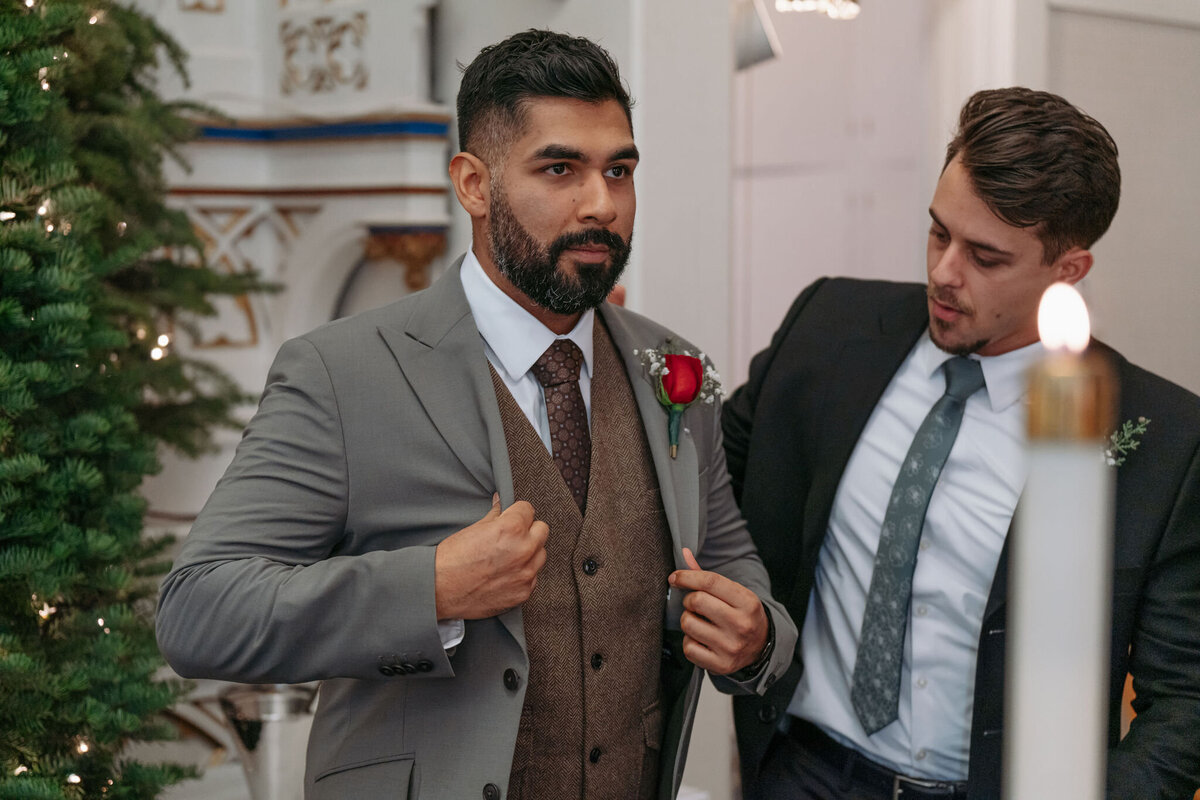 a groom putting on his suit jacket