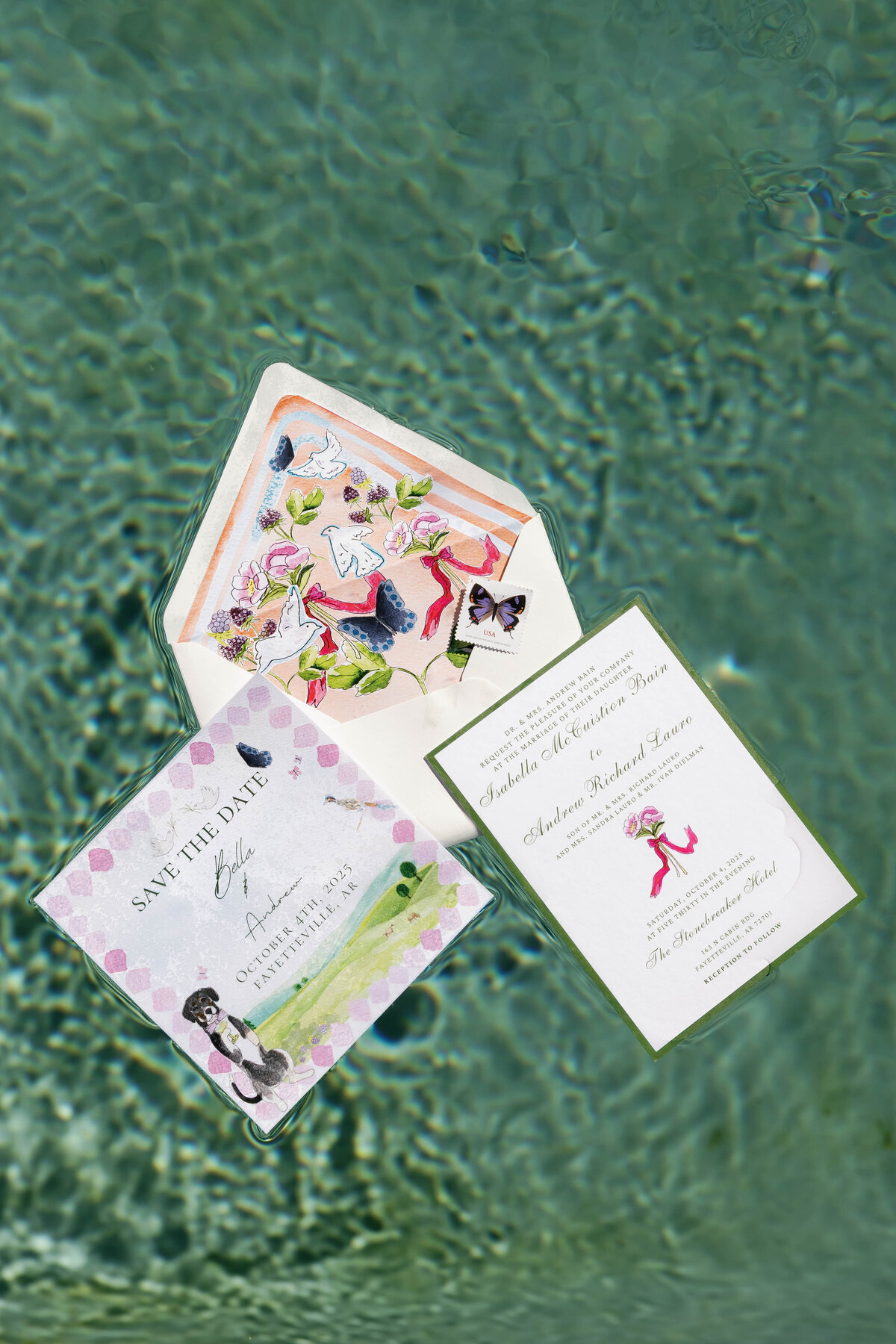 Wedding invitations and save-the-date cards floating artistically in clear, rippled water. The stationery features watercolor illustrations of dogs, florals, ribbons, and butterflies in soft pastel tones, creating a whimsical and artistic wedding flat-lay with a unique underwater effect.